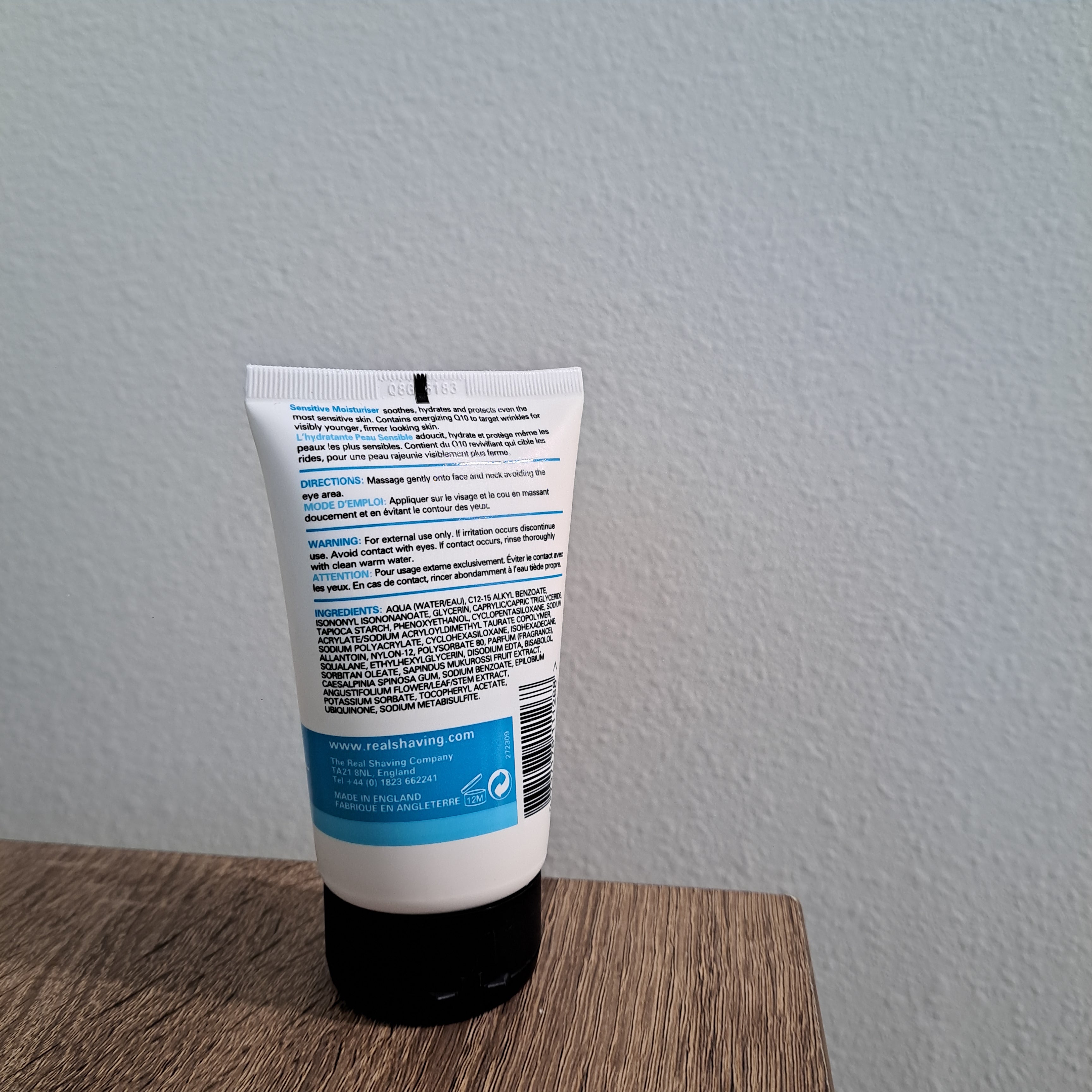 Tube of lotion on a white surface with a gray wall background