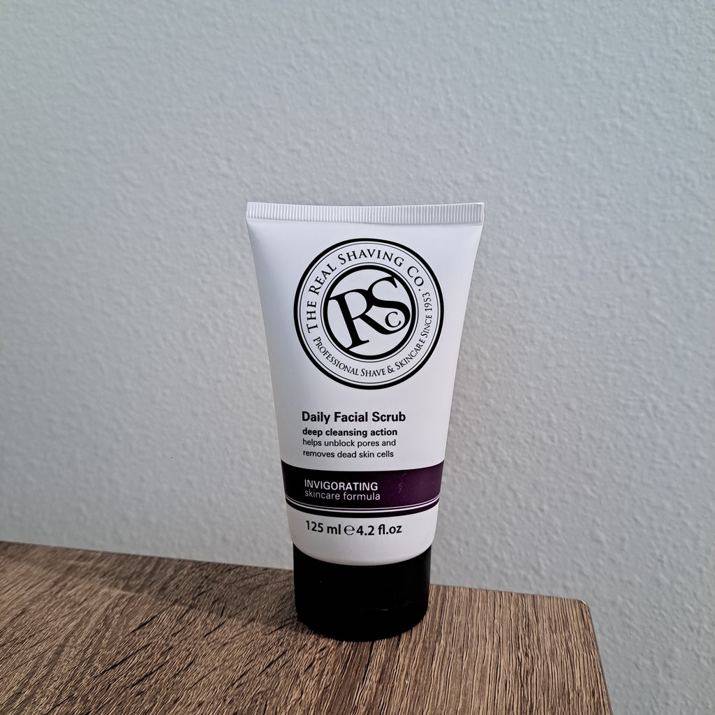 Tube of Daily Facial Scrub on a white surface with a wooden edge
