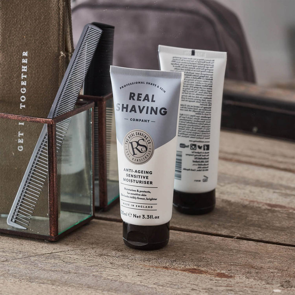 Real Shaving Company products on a wooden surface with a comb and bag in the background.
